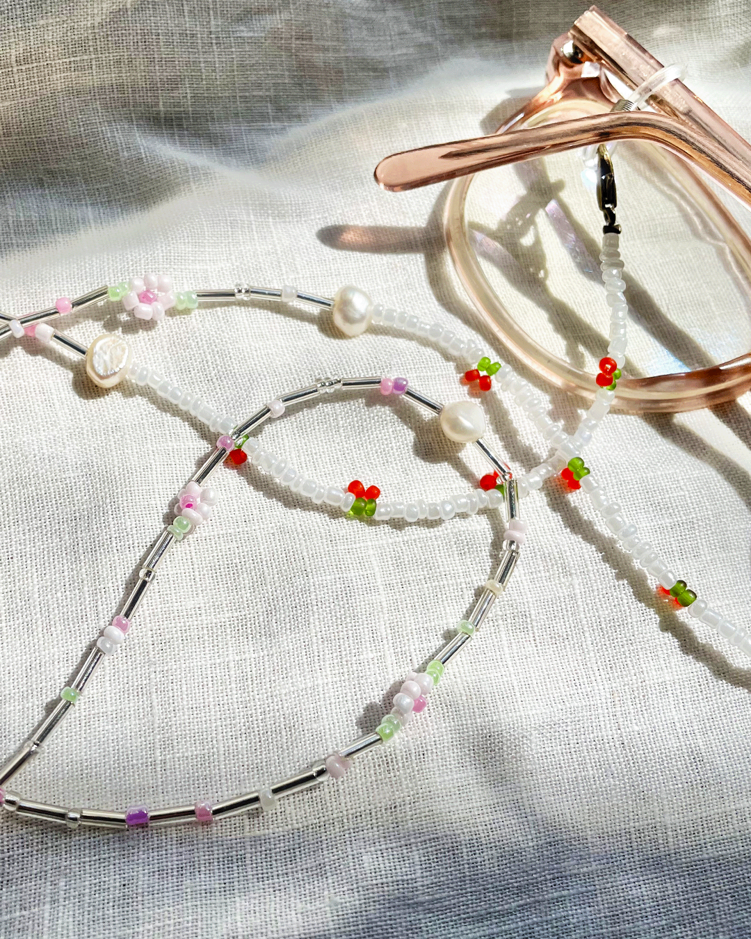 Silver glasses chain with colorful beads on a textured fabric background