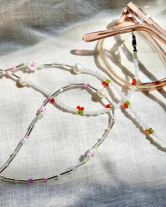 Silver glasses chain with colorful beads on a textured fabric background