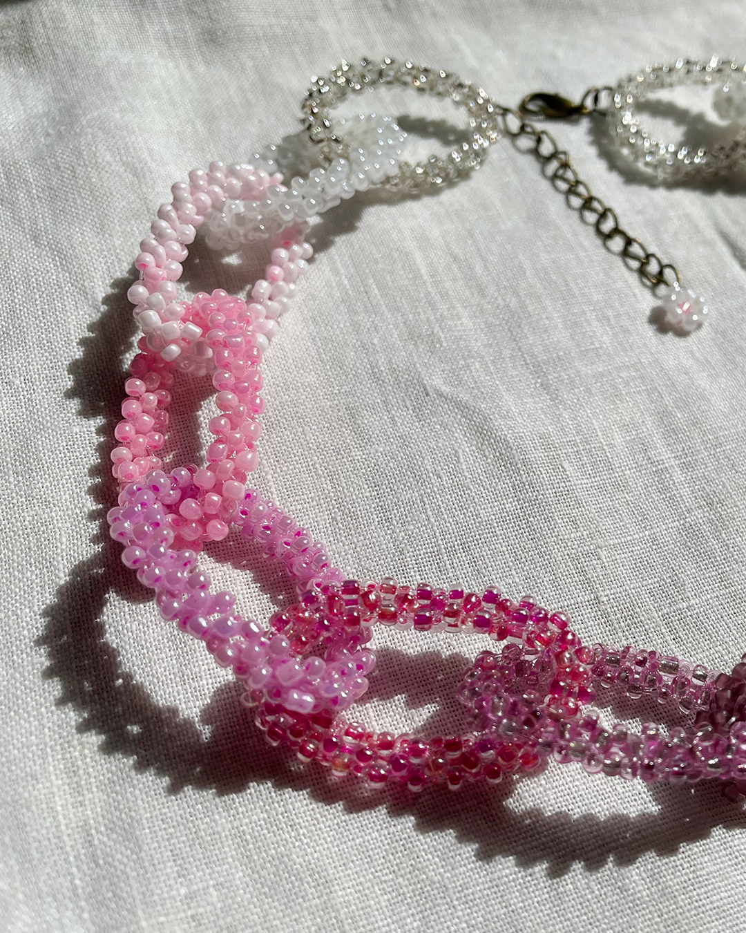 Pink beaded necklace on a light fabric background