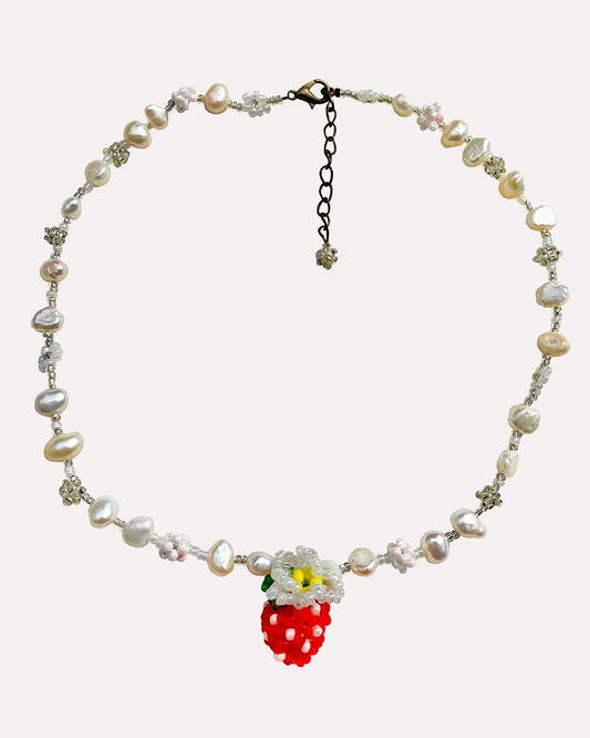 Necklace with pearls and beads and a strawberry charm on a white background