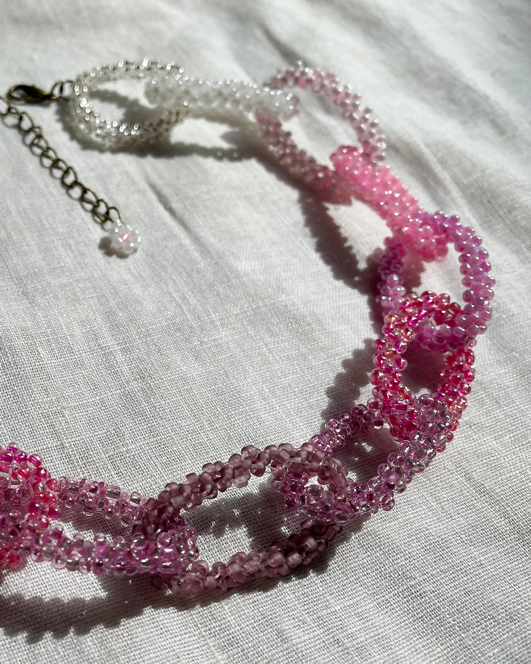 Pink beaded necklace on a light fabric background