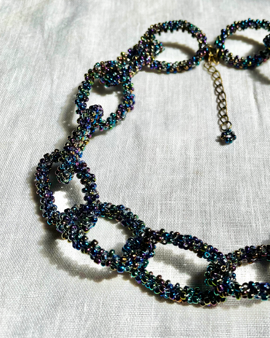 Black Rainbow beaded necklace on a white fabric background