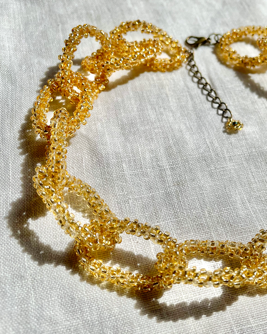 Gold beaded necklace on a light fabric background