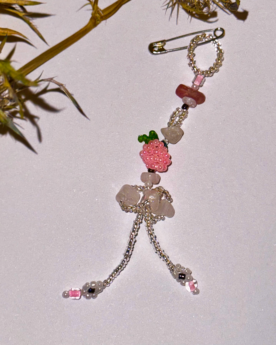 Beaded pin with pink flowers and pink quartz on a light background
