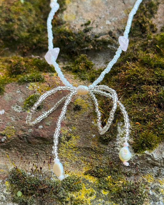 Necklace with a bow pendant on a textured stone surface