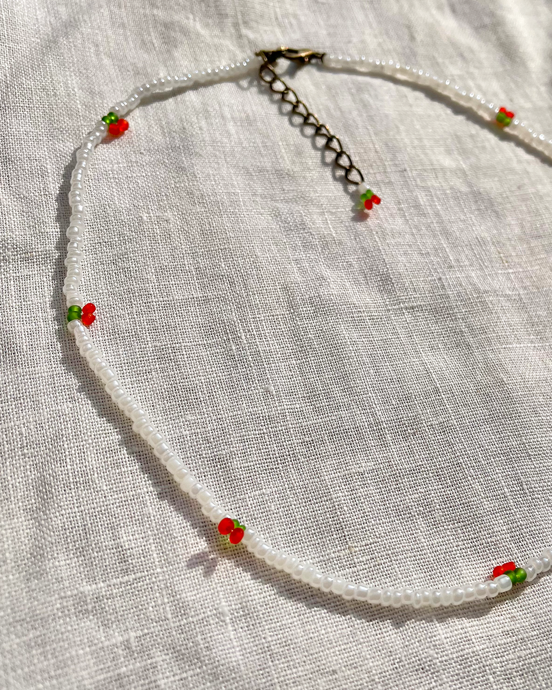 Necklace with small cherries on a light fabric background