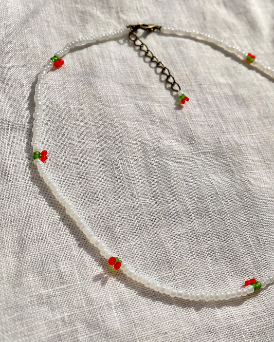 Necklace with small cherries on a light fabric background