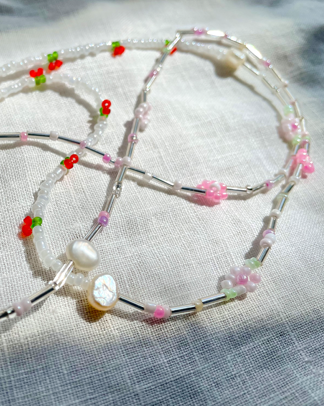 Beaded glasses chain with pearls and floral beads on a textured fabric background