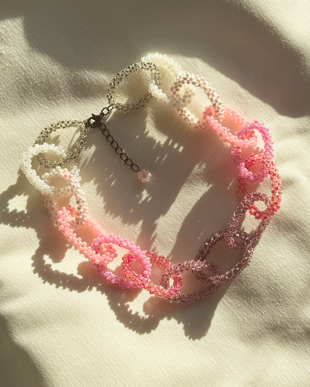 Pink beaded necklace on a light fabric background