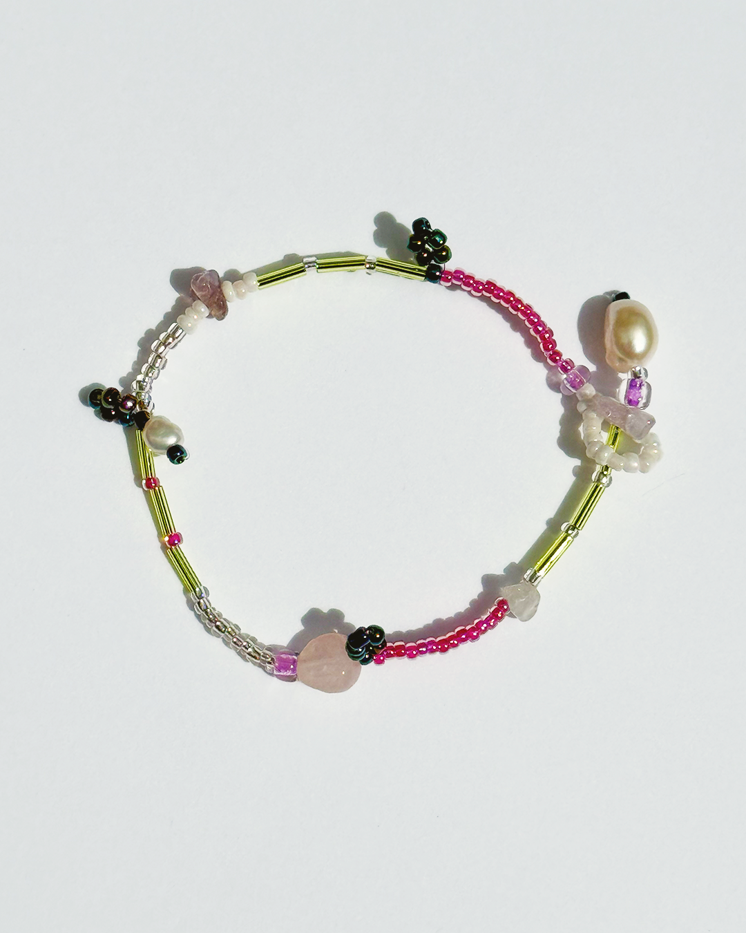 Colourful beaded bracelet on a white background with pearls and pink quartz