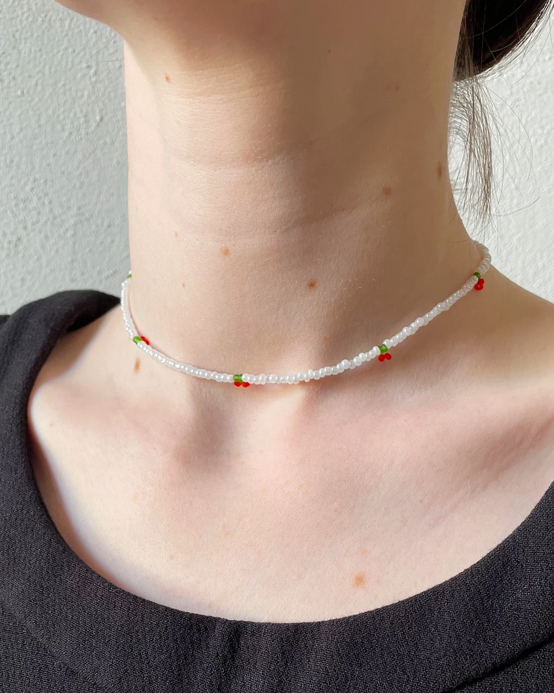 Close-up of a delicate beaded necklace against a neutral background