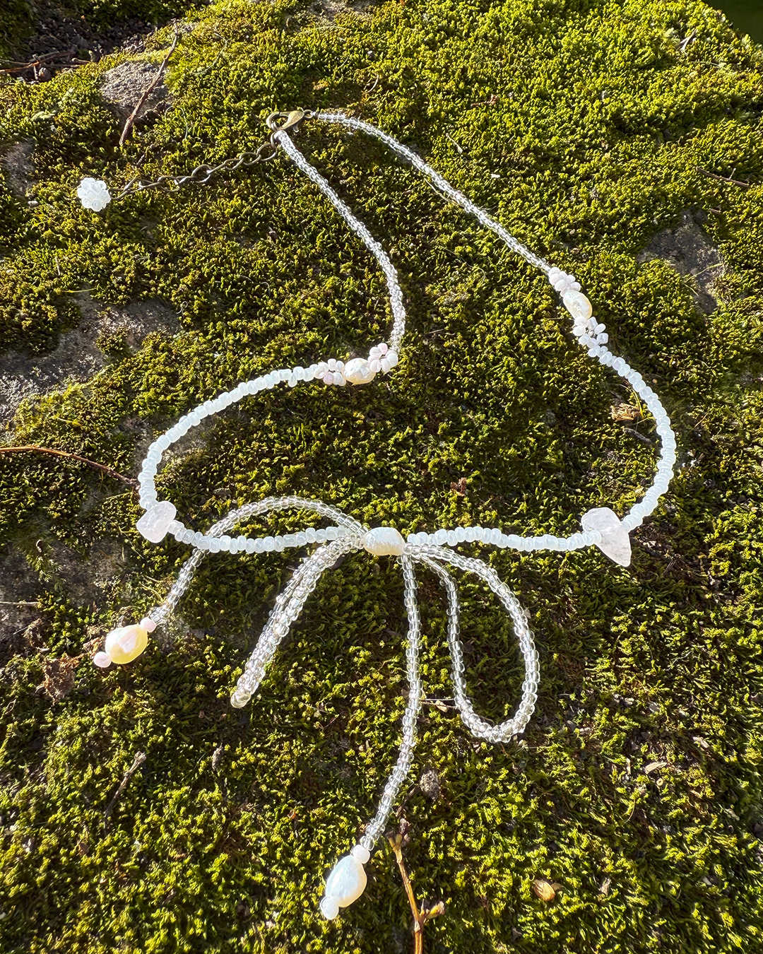 Necklace with white beads on a green moss background