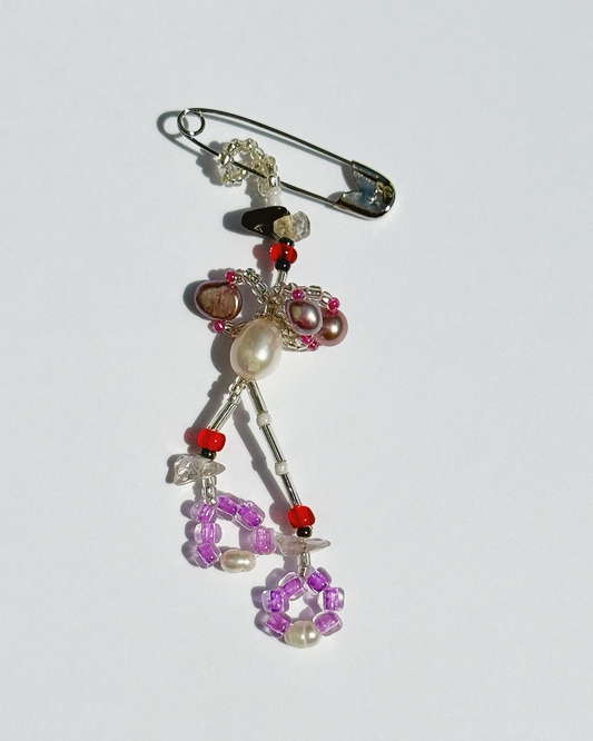 Beaded decorative pin  with colourful beads and pearls on a white background
