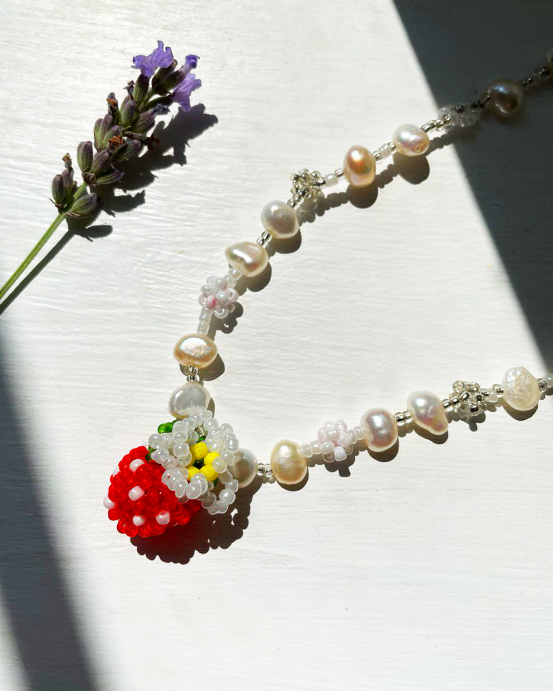 Pearl necklace with a red berry pendant on a white background