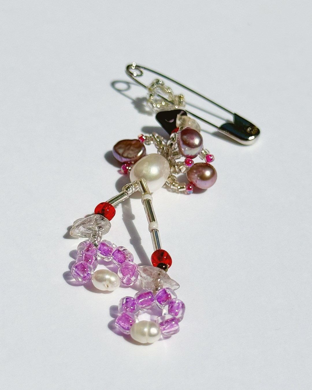 Beaded decorative pin  with colourful beads and pearls on a white background