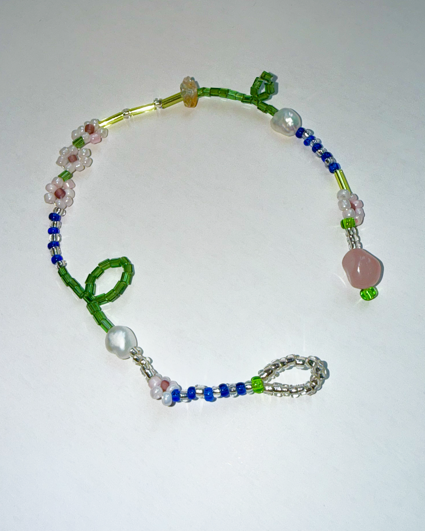Beaded necklace with green, blue, and pink beads on a white background