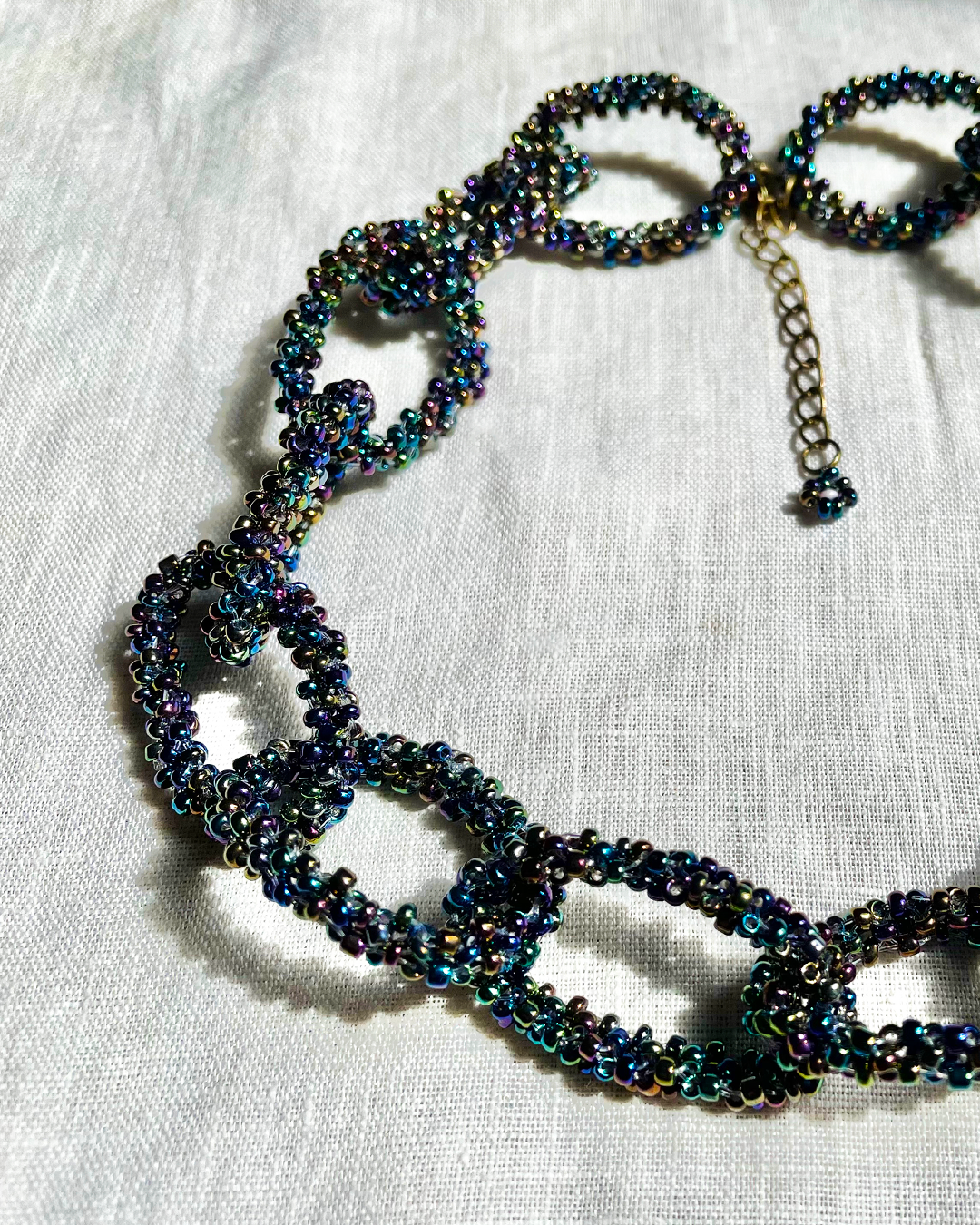 Black Rainbow beaded necklace on a white fabric background
