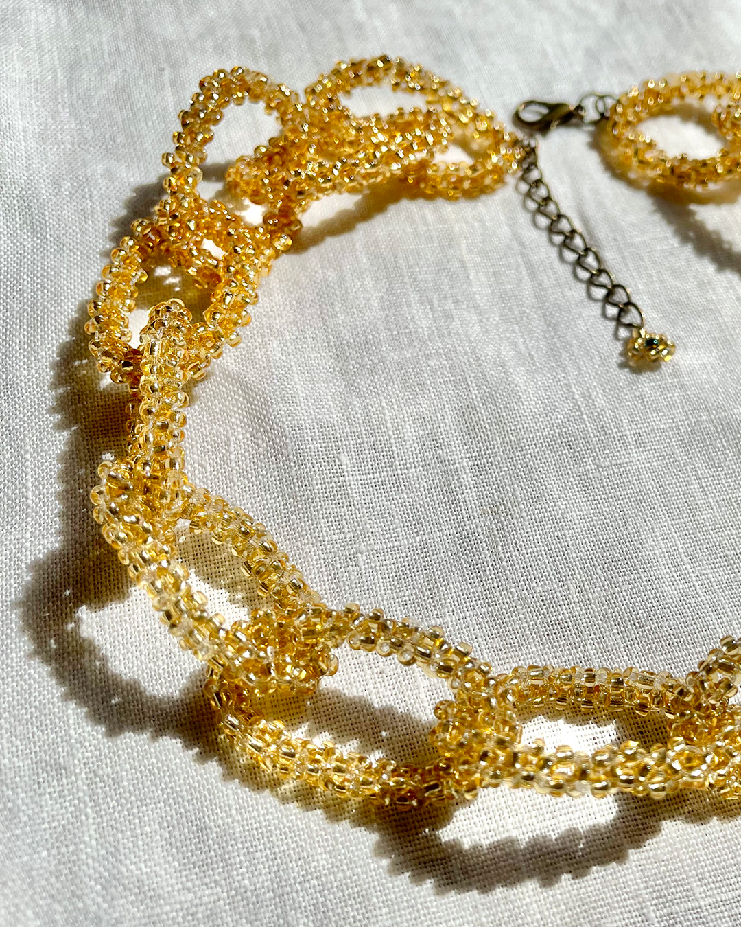 Gold beaded necklace on a light fabric background