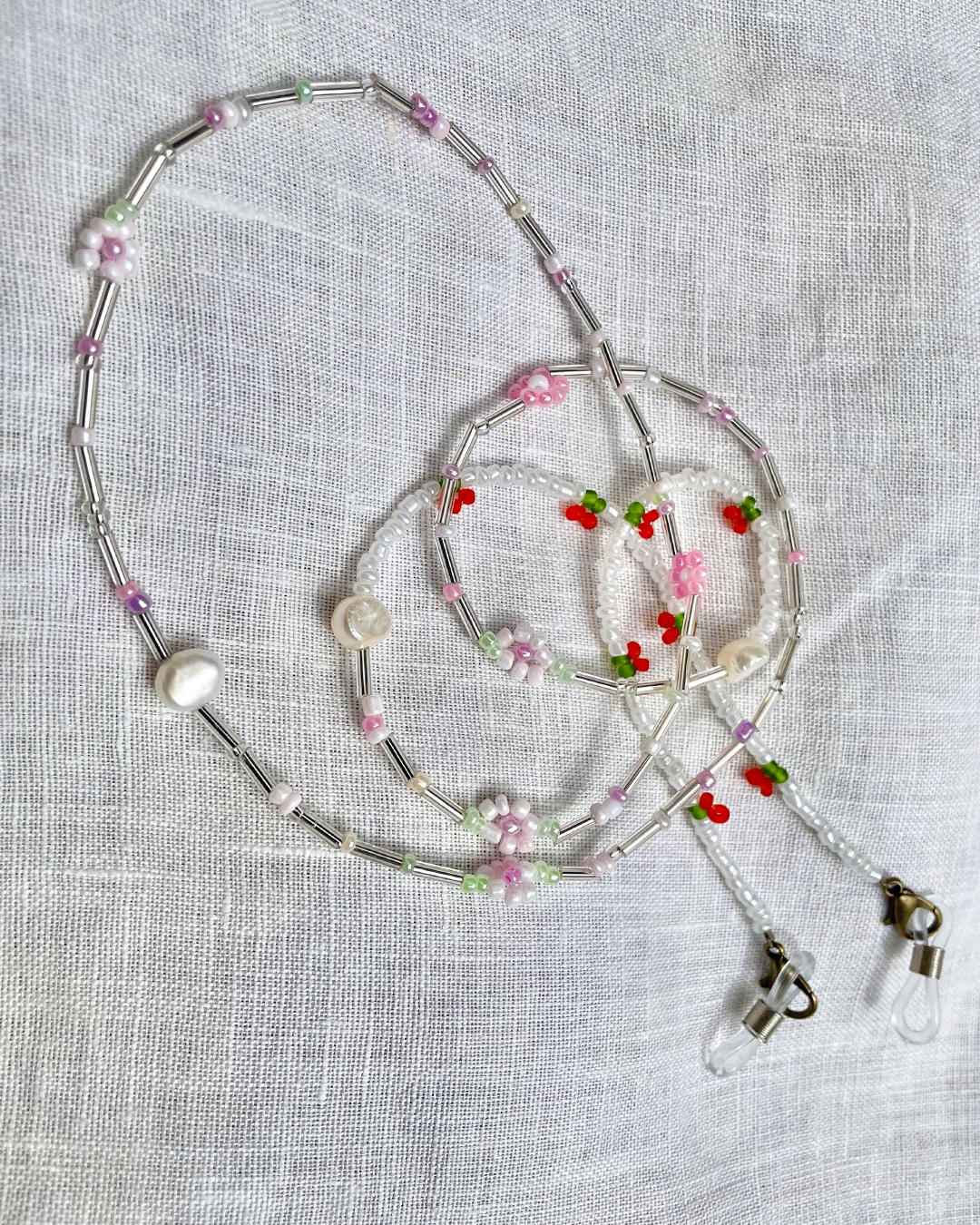 Beaded glasses chain with floral decorations on a light gray fabric background