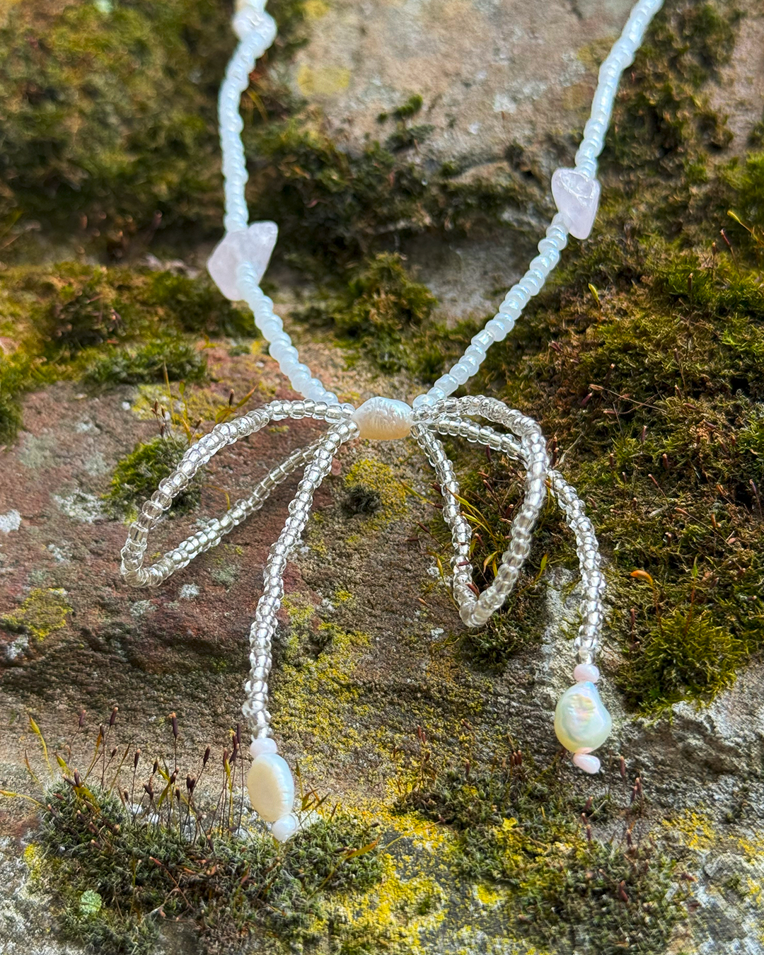 Necklace with a bow pendant on a textured stone surface