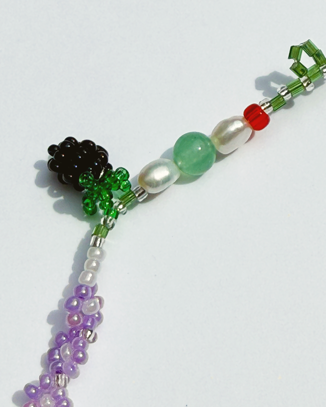 A beaded blackberry with jade beads and fresh water pearls on white background