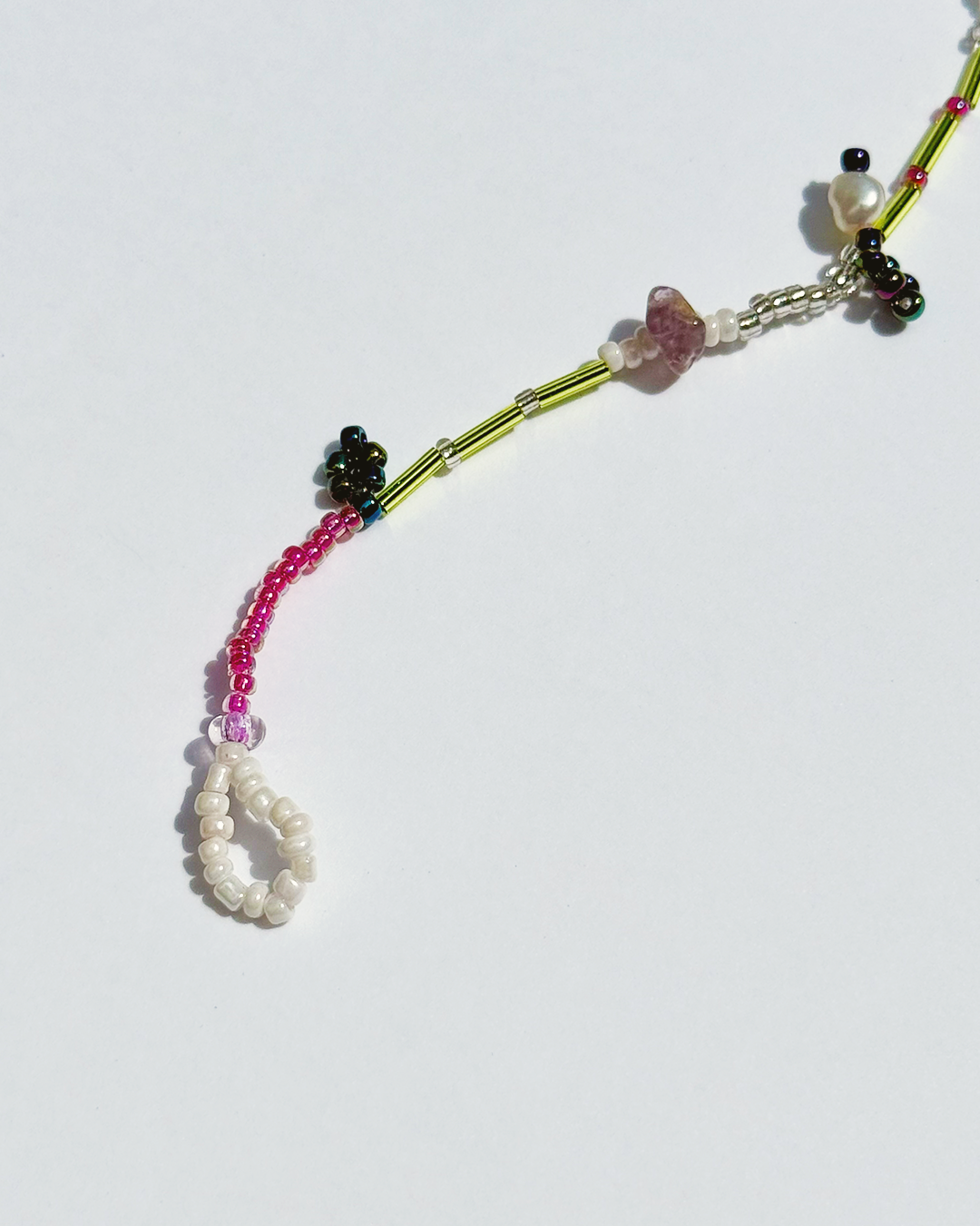 DIY closure of a colourful beaded bracelet on a white background with pearls and pink quartz