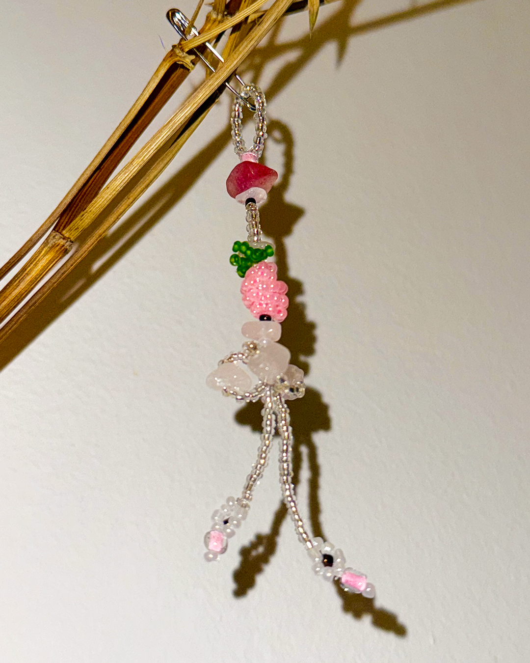 Beaded charm with pink and green beads on a white background