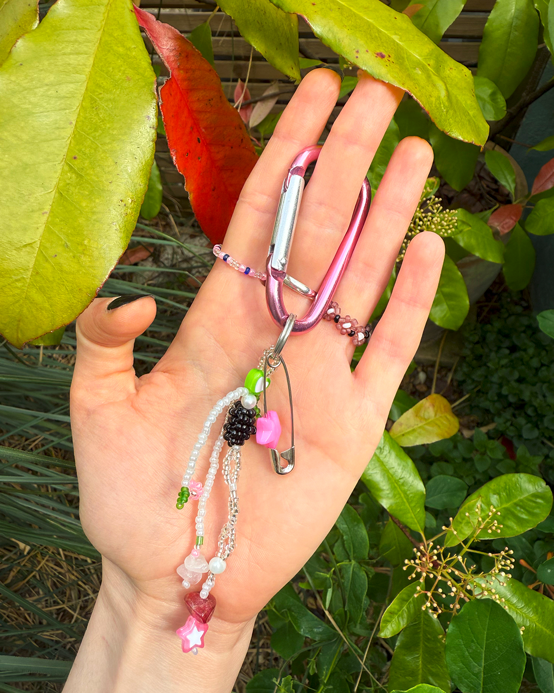 Hand holding a colorful keychain with a green leafy background