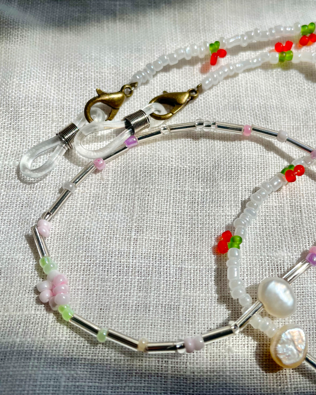 Handmade glasses chain with floral beads and a clasp on a light fabric background