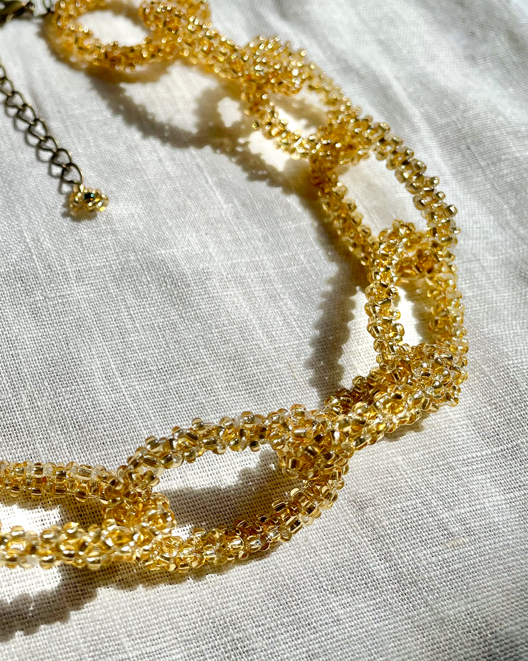 Gold beaded necklace on a light fabric background