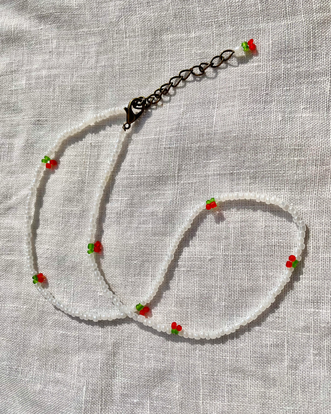 Necklace with red cherries on a light fabric background