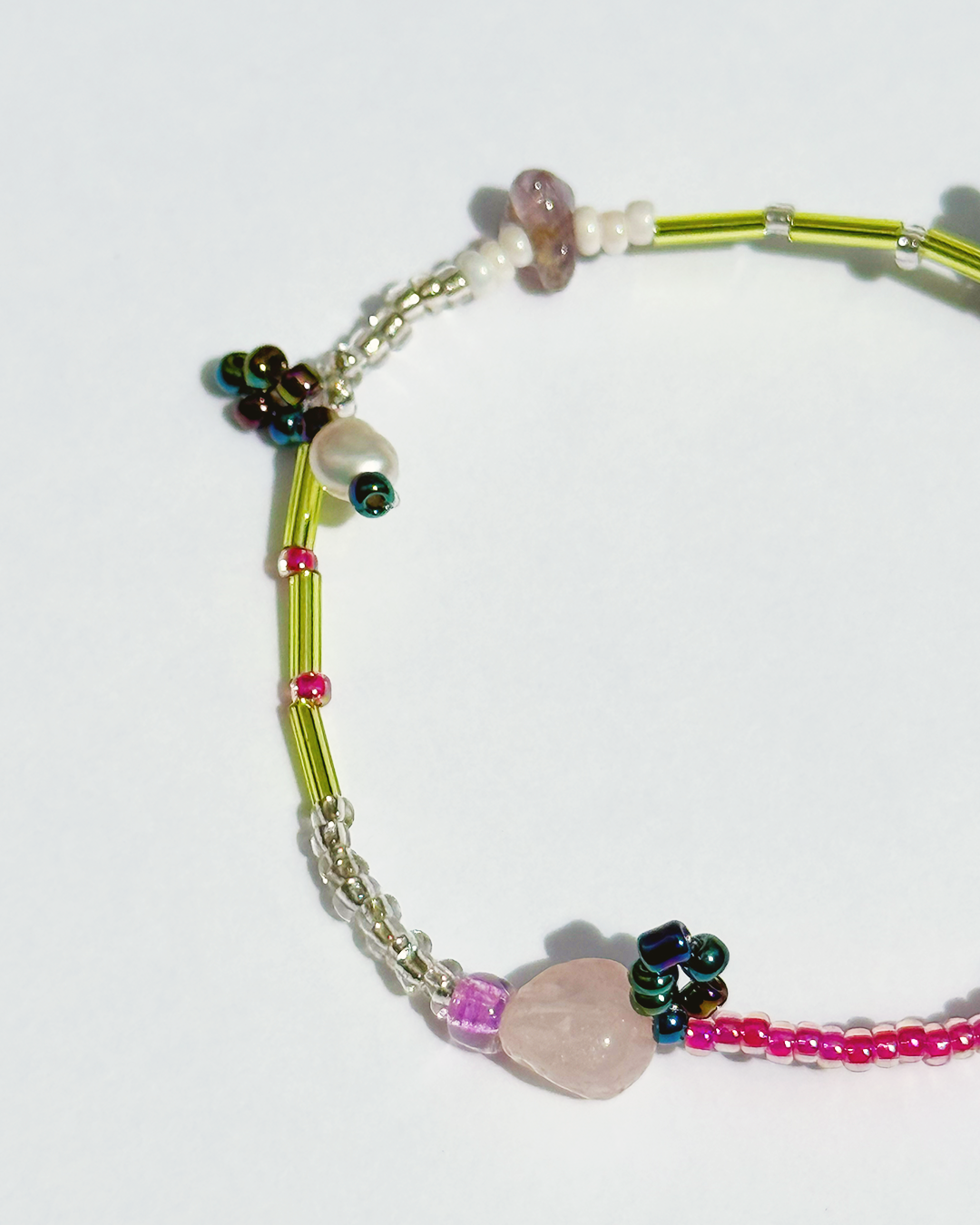 Part of a colourful beaded bracelet on a white background with pearls and pink quartz