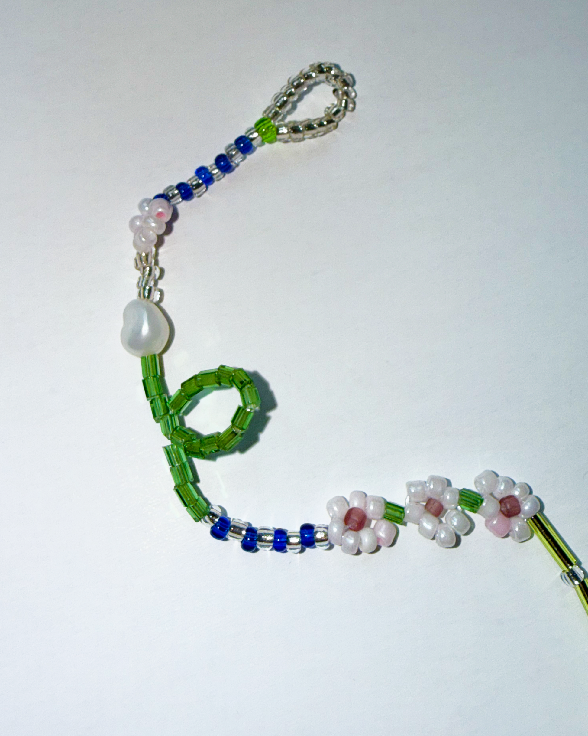Beaded bracelet with green, blue, and white beads on a white background