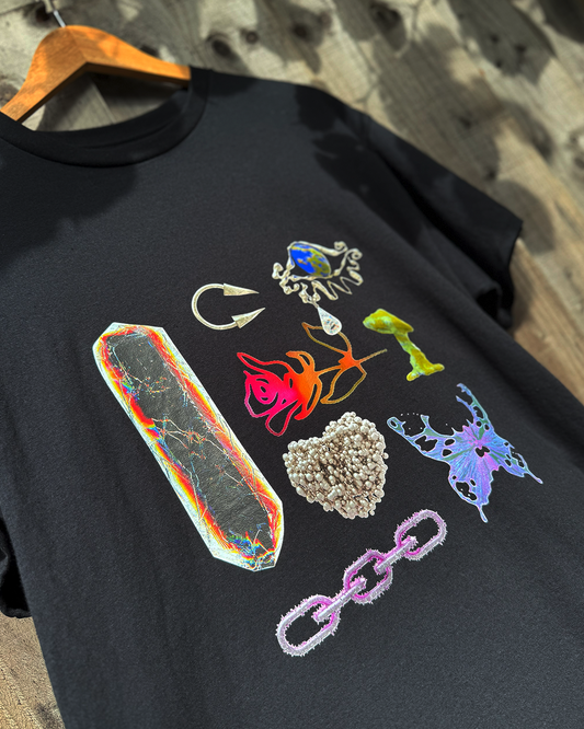 black t-shirt with a mushroom, crystal & butterfly print hanging on a fence
