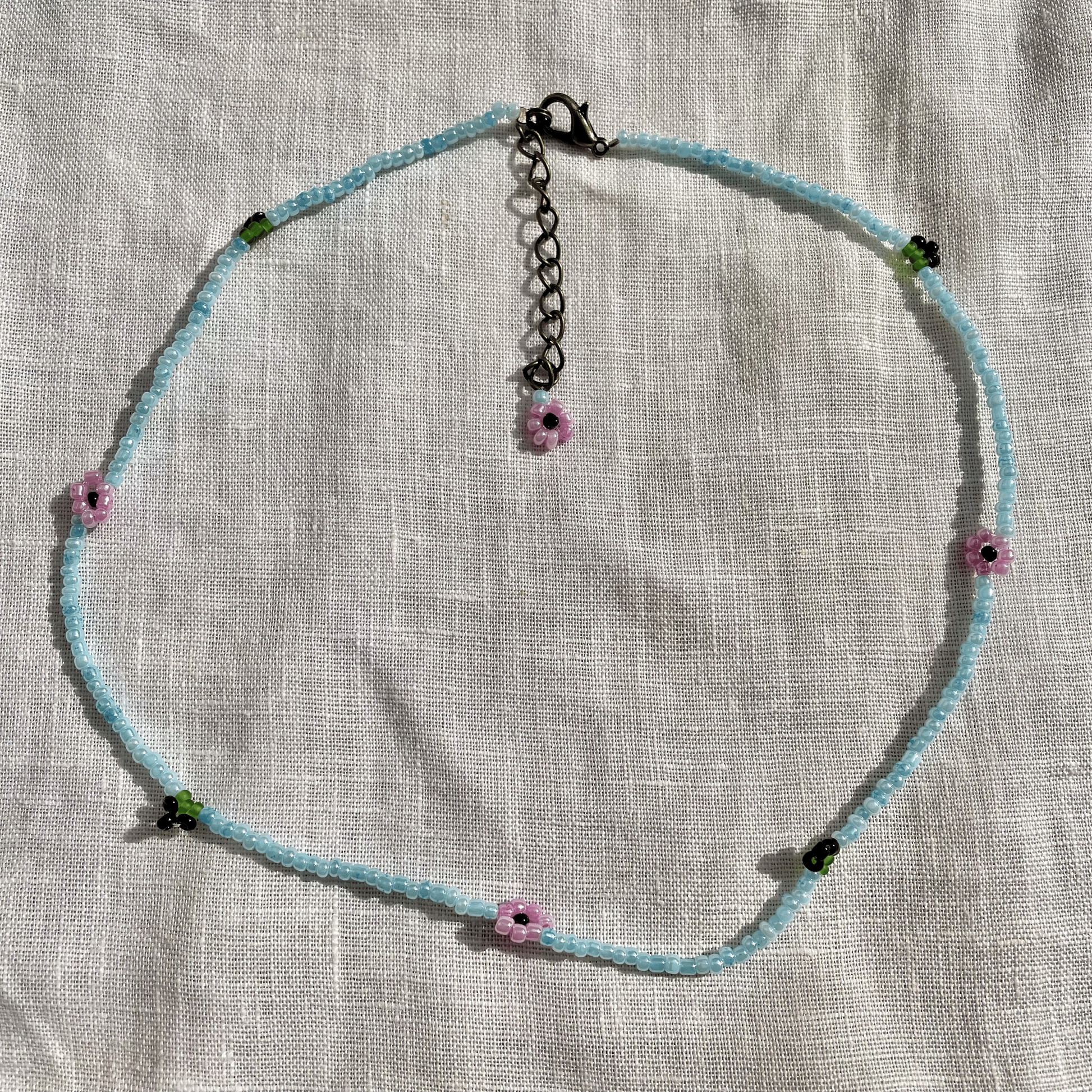 Necklace with floral beads on a textured fabric background
